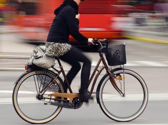 a woman pedaling a bike quickly down the street