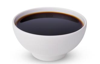 A thick brown liquid inside of a small ceramic bowl; the liquid appears uniform throughout.