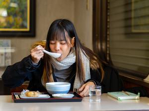 A woman eating soup inside a restaurant.