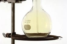 A pale yellow gas inside of a glass flask.