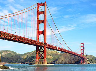a large, steel, orange bridge over water connecting large hills