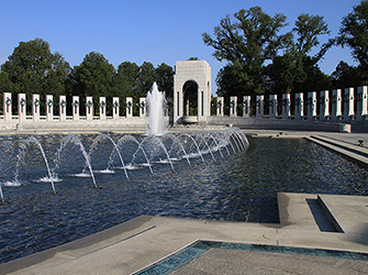There are pillars and arches surrounding a plaza and fountain.