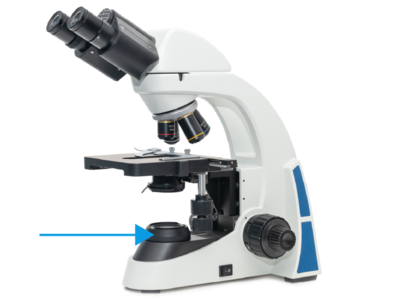 An arrow points to a part of a light microscope.