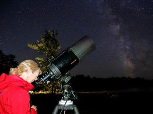 a woman observing the night sky through a telescope