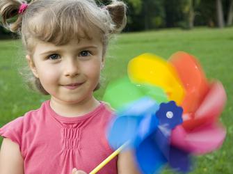 A kid holds a pinwheel toy. The pinwheel is spinning.