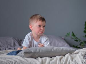 a little boy looking sad and angry on a bed