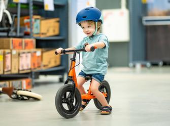 a boy pushing a balance bike with his feet