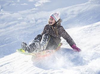 a child riding a sled down a hill